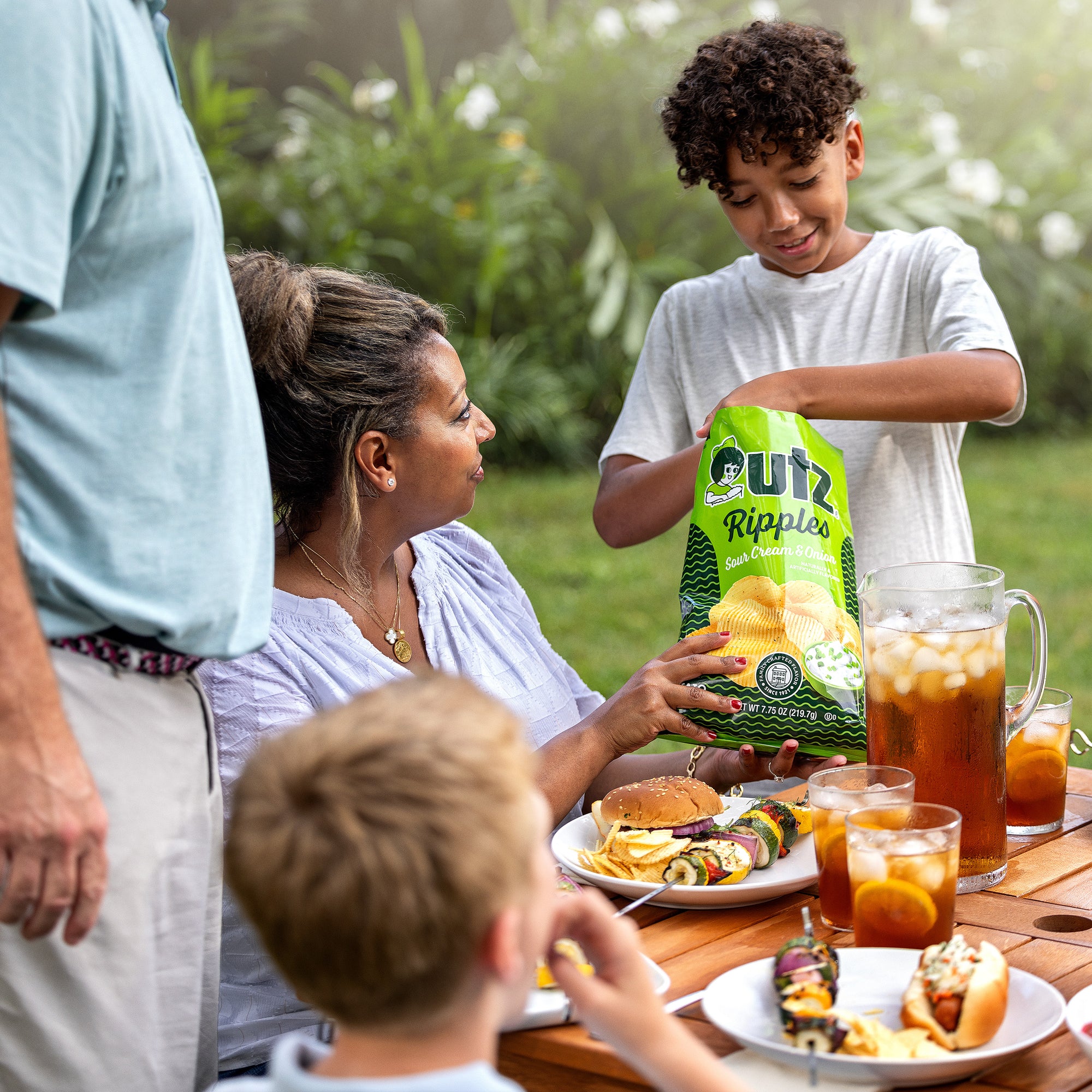 Family enjoying a meal outdoors with a bag of Cuts Ripples chips.