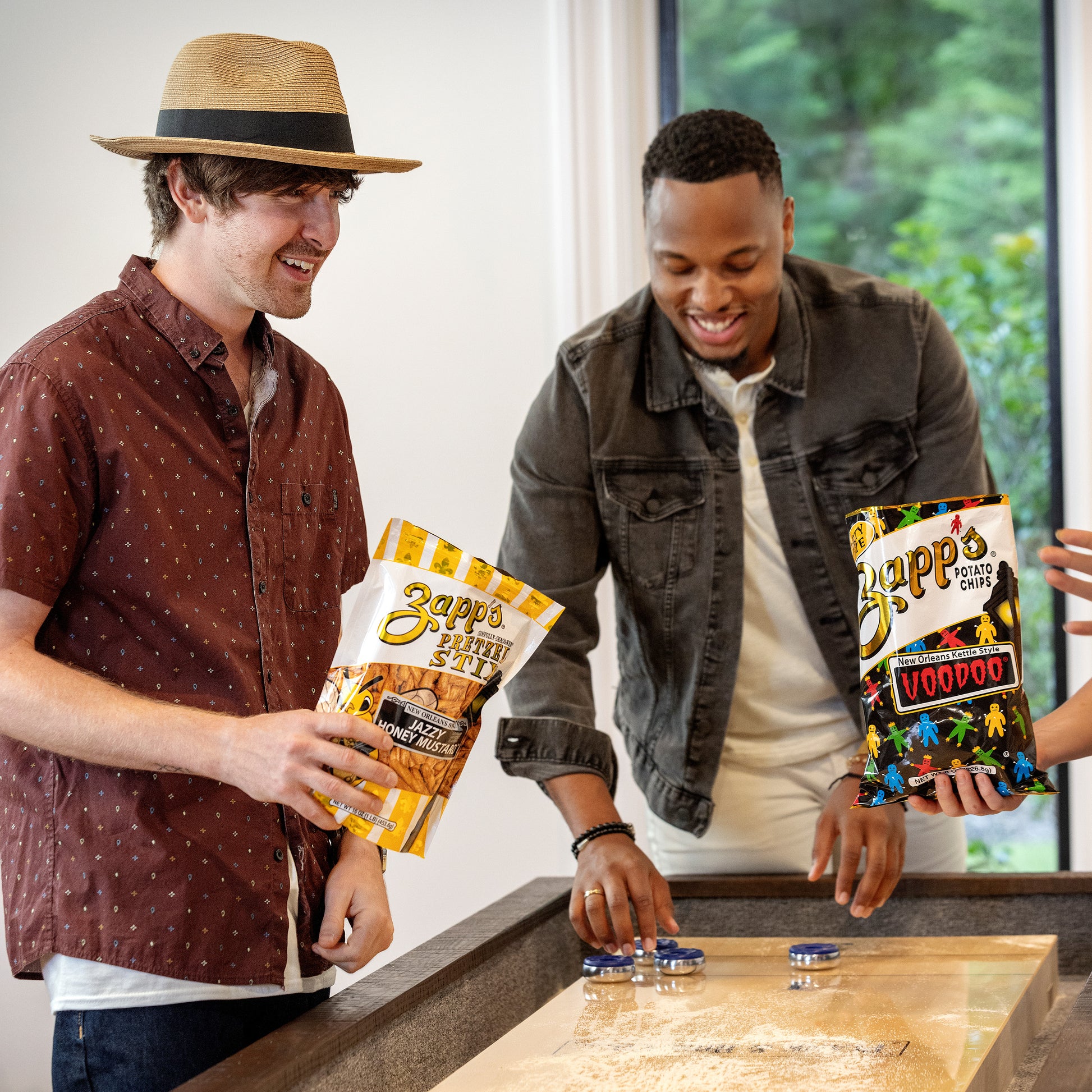 Two men holding Zapp's products in a casual setting