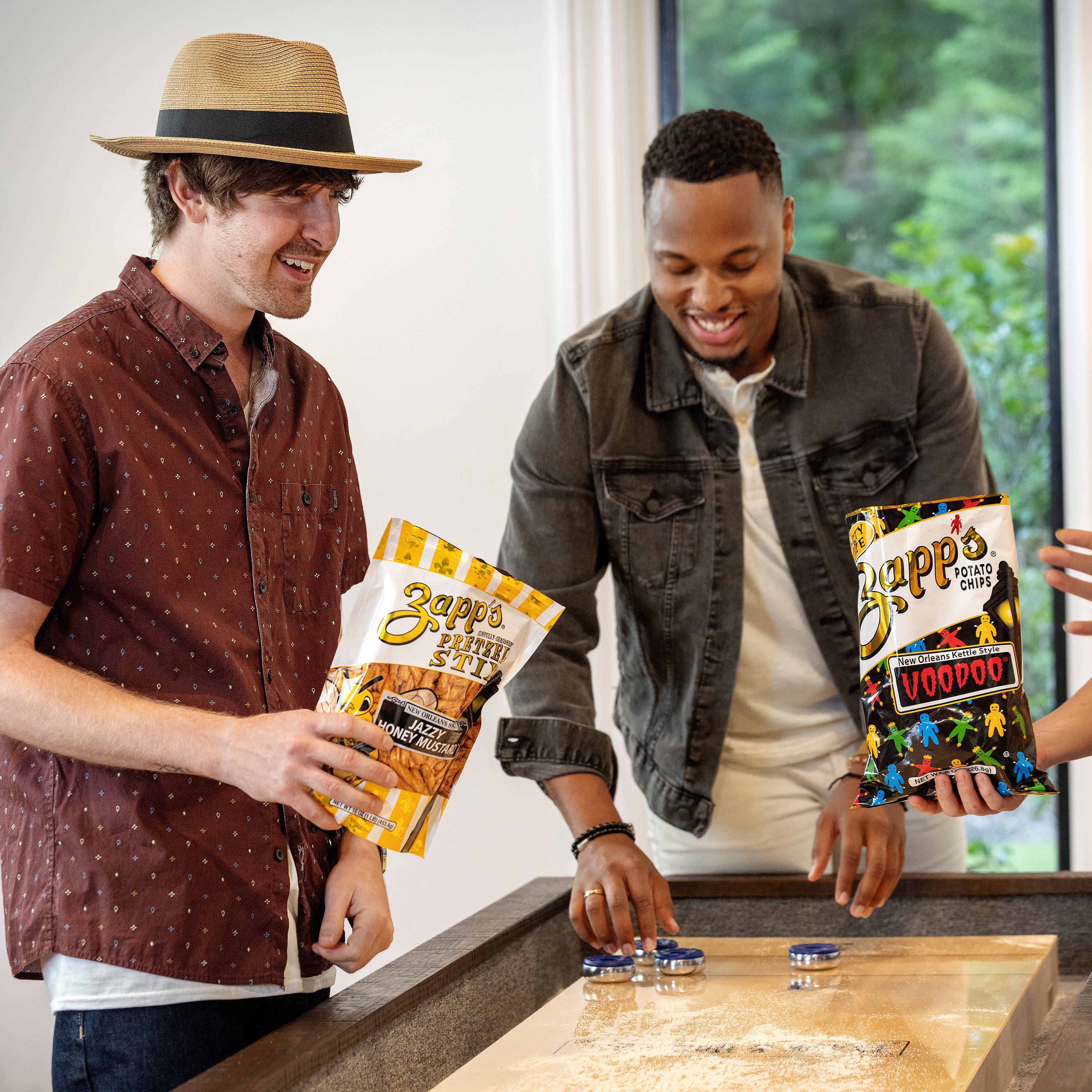 Two men holding Zapp's products in a casual setting