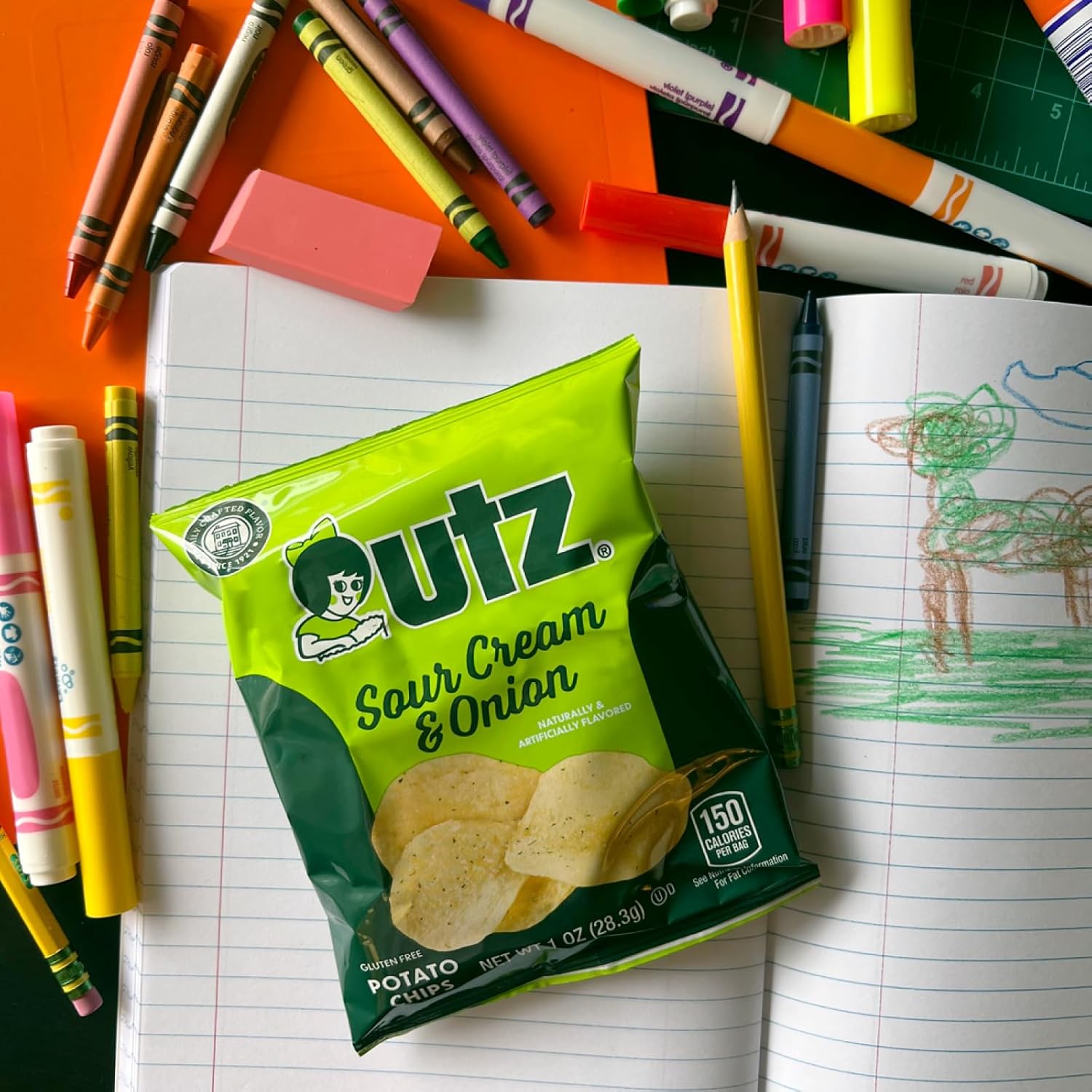 Outz Sour Cream & Onion potato chips packet on a desk with school supplies
