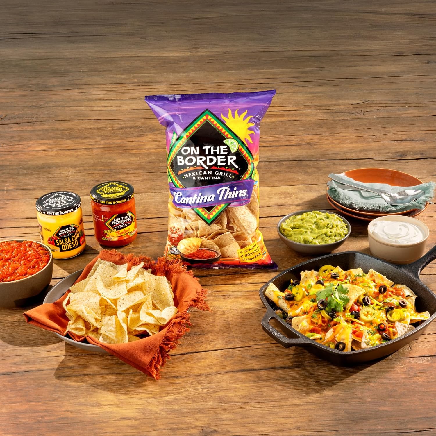 On The Border tortilla chips with nachos and condiments on a wooden table