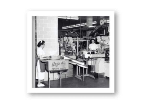 Vintage black and white photo of a store interior with a woman at a counter.