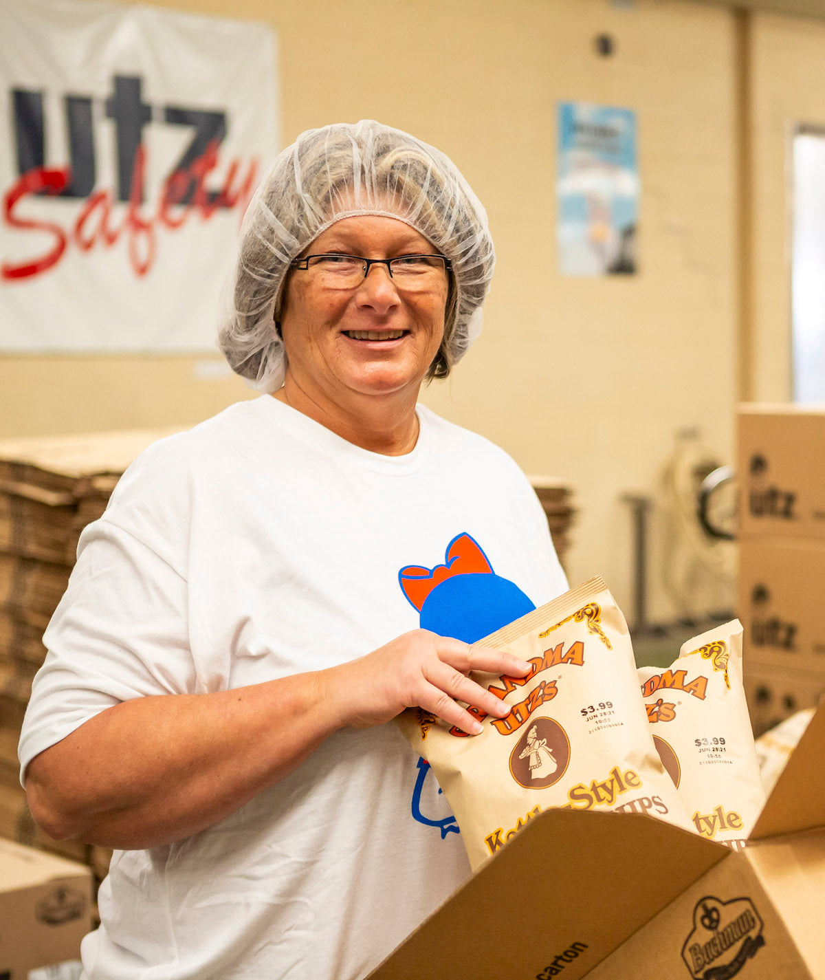 Person in a hairnet holding a package in a warehouse setting with Utz Safely branding.