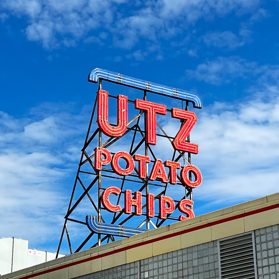 Neon sign for UTZ Potato Chips against a blue sky