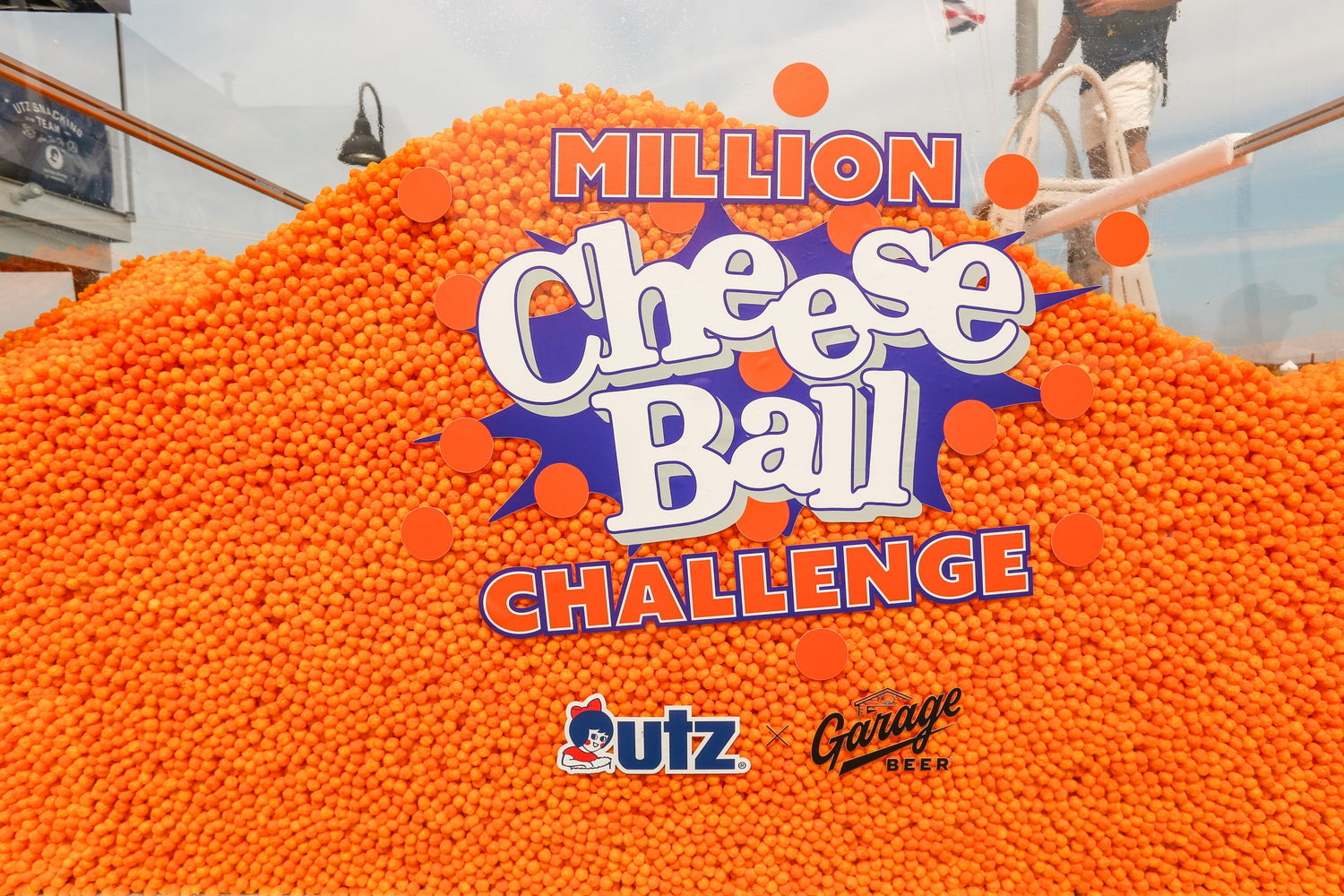 A pool filled with more than one million orange Utz Cheese Balls behind the Utz x Garage Beer Million Cheese Ball Challenge sign at Beer Bowl 2026 in Sea Isle City, New Jersey.