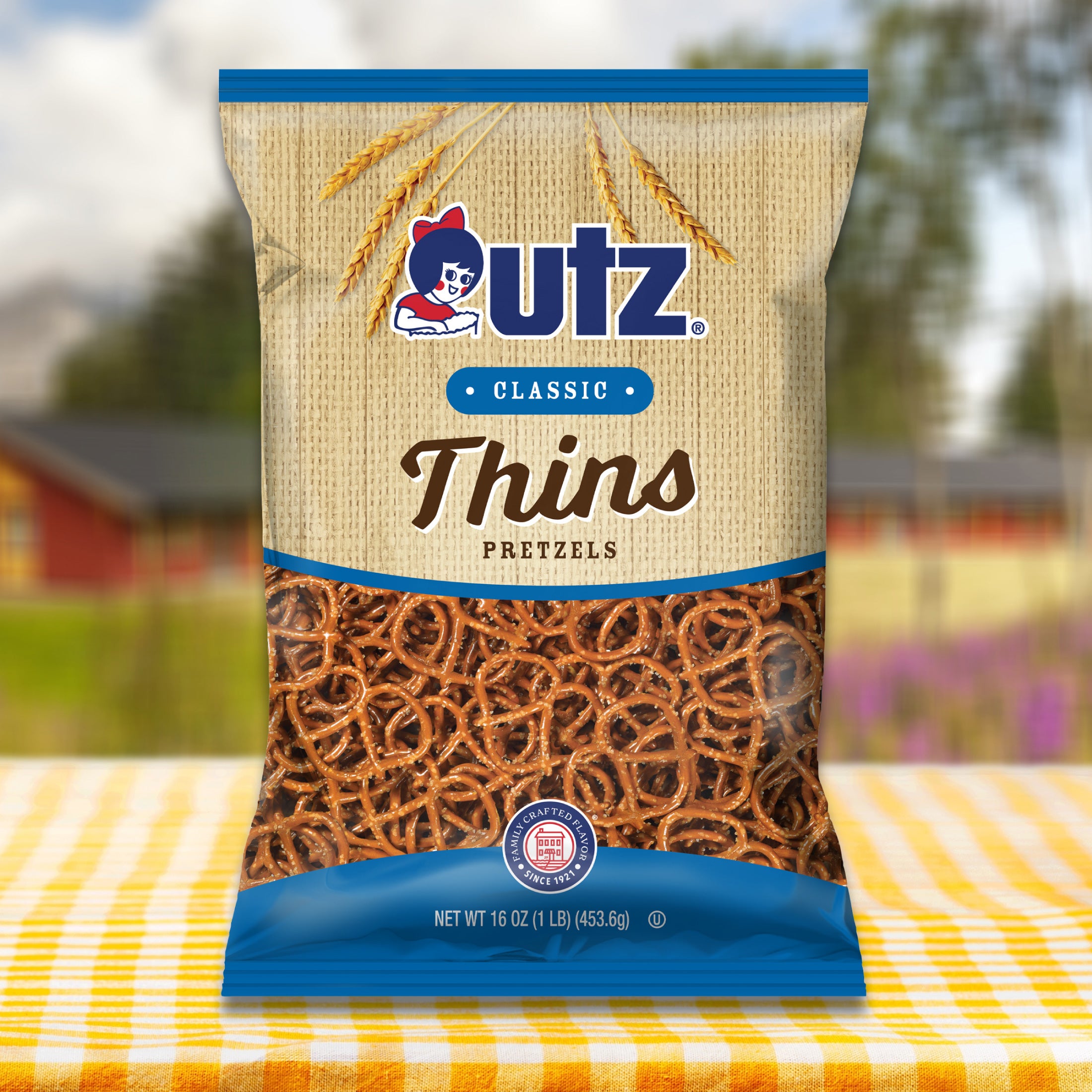 Outz Classic Thins Pretzels package on a table with a blurred outdoor background
