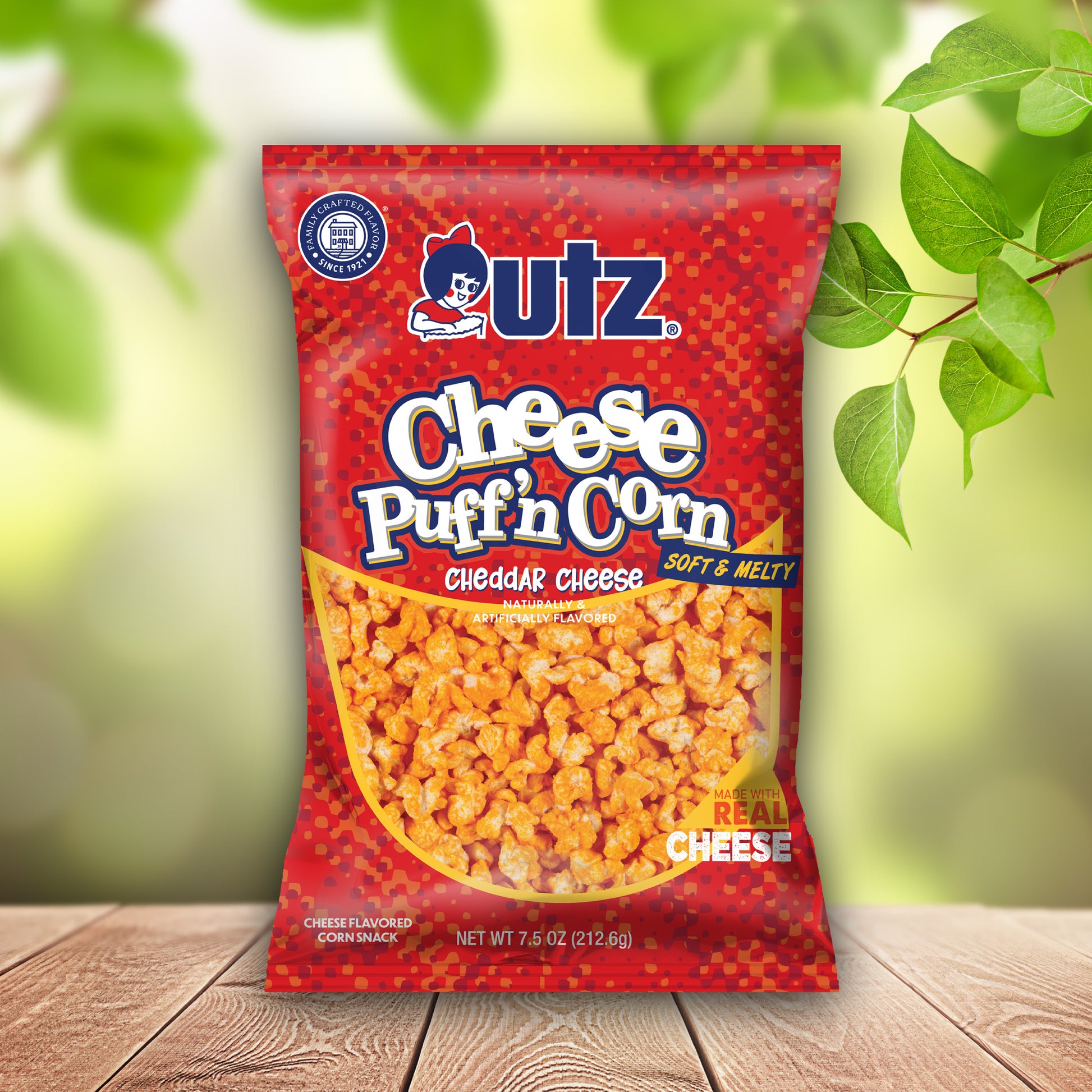 UTZ Cheese Puff'n Corn package on a wooden surface with a blurred green background