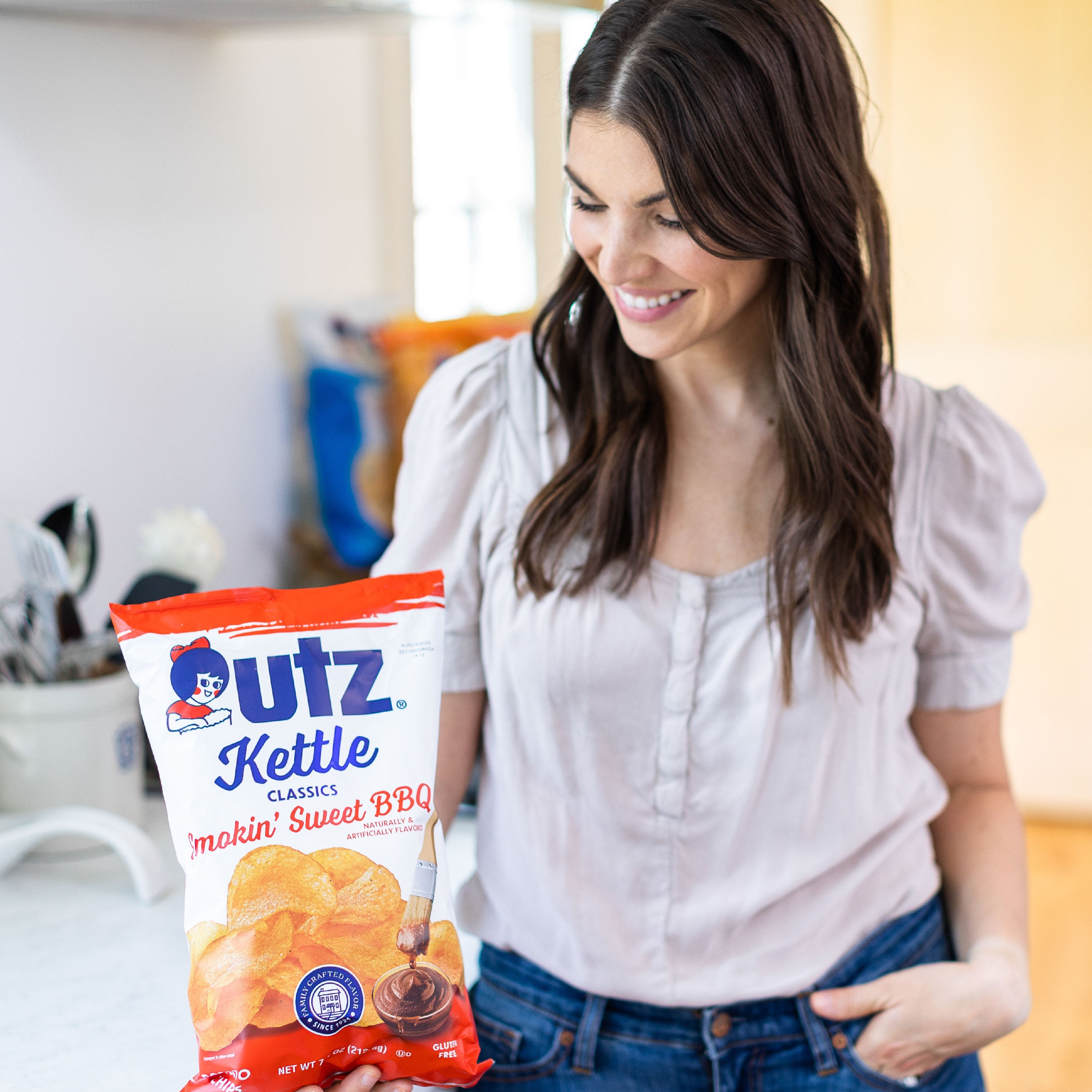 Woman holding a bag of Utz Kettle Classics makin' Sweet BBQ flavored chips.