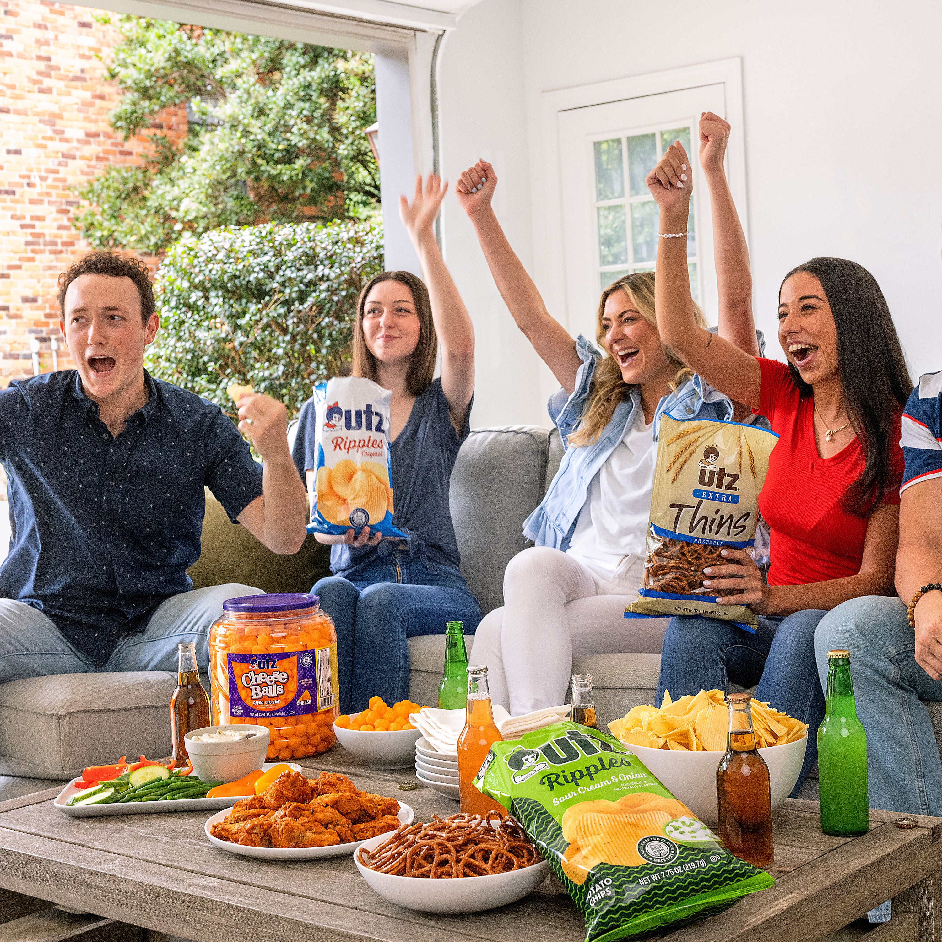 Group of friends cheering and enjoying snacks and drinks on a patio.