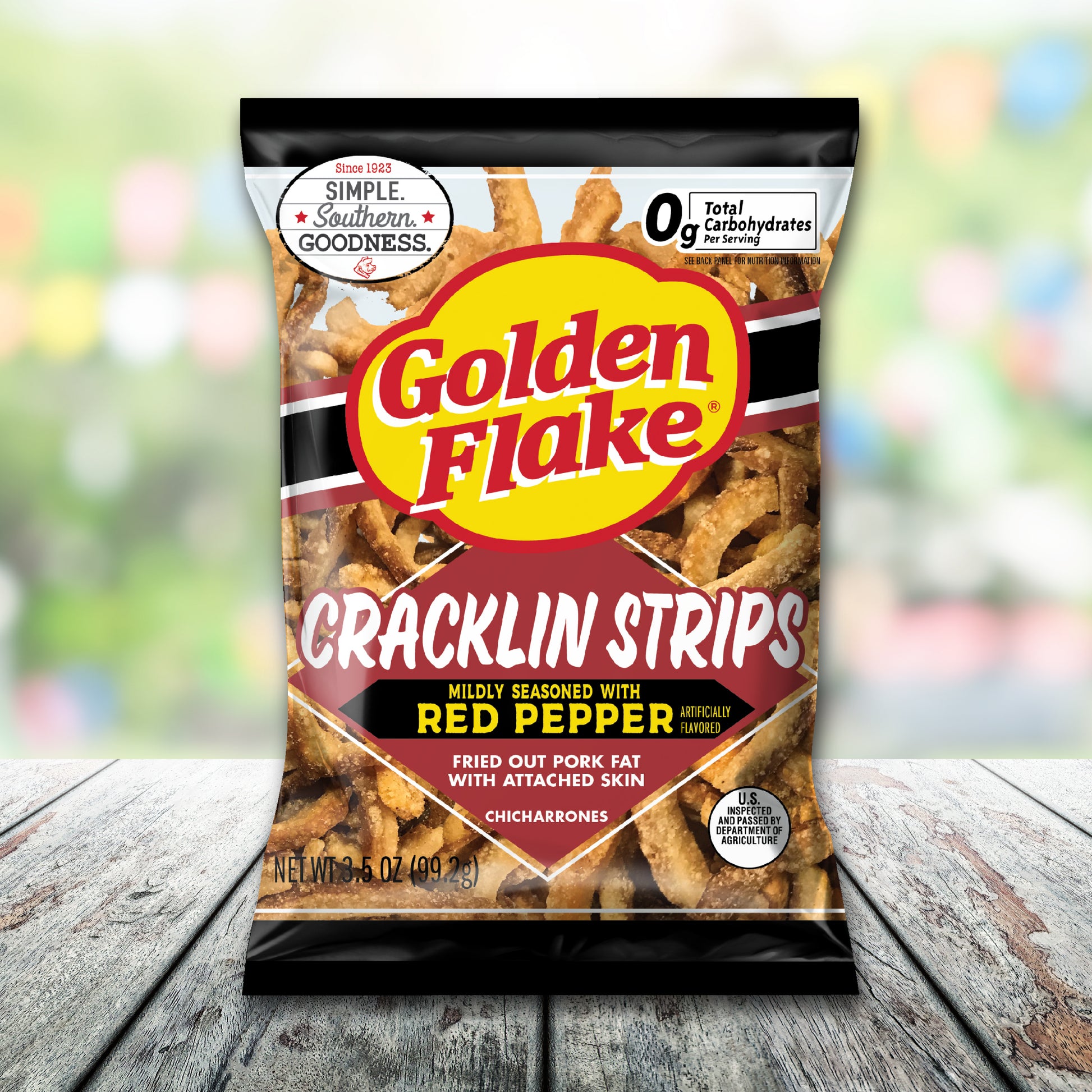 Packaging of Golden Flake Cracklin Strips on a wooden surface with a blurred colorful background