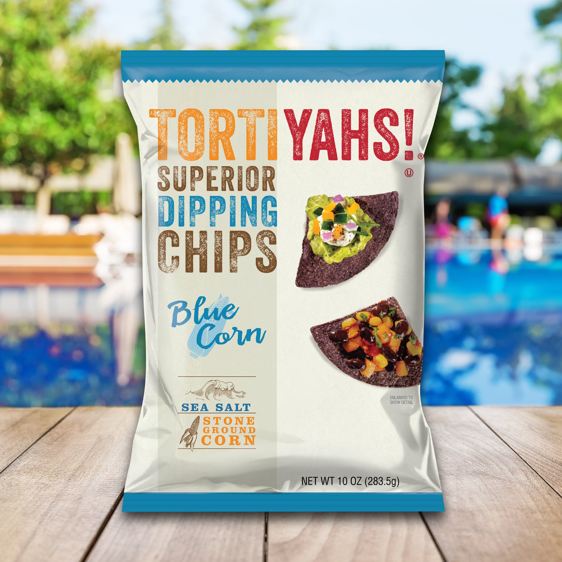 Tortiyahs! Blue Corn Superior Dipping Chips packaging on a wooden surface with a blurred outdoor background.
