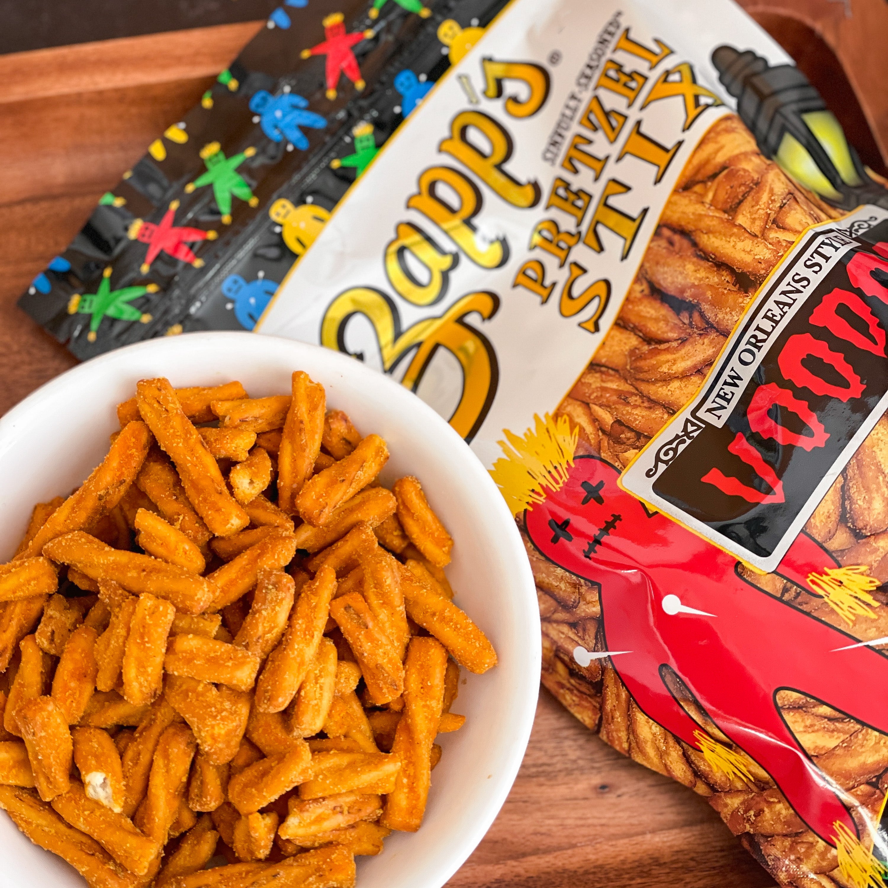 Pretzel sticks in a bowl with Zapp's Pretzel Stix packaging in the background.