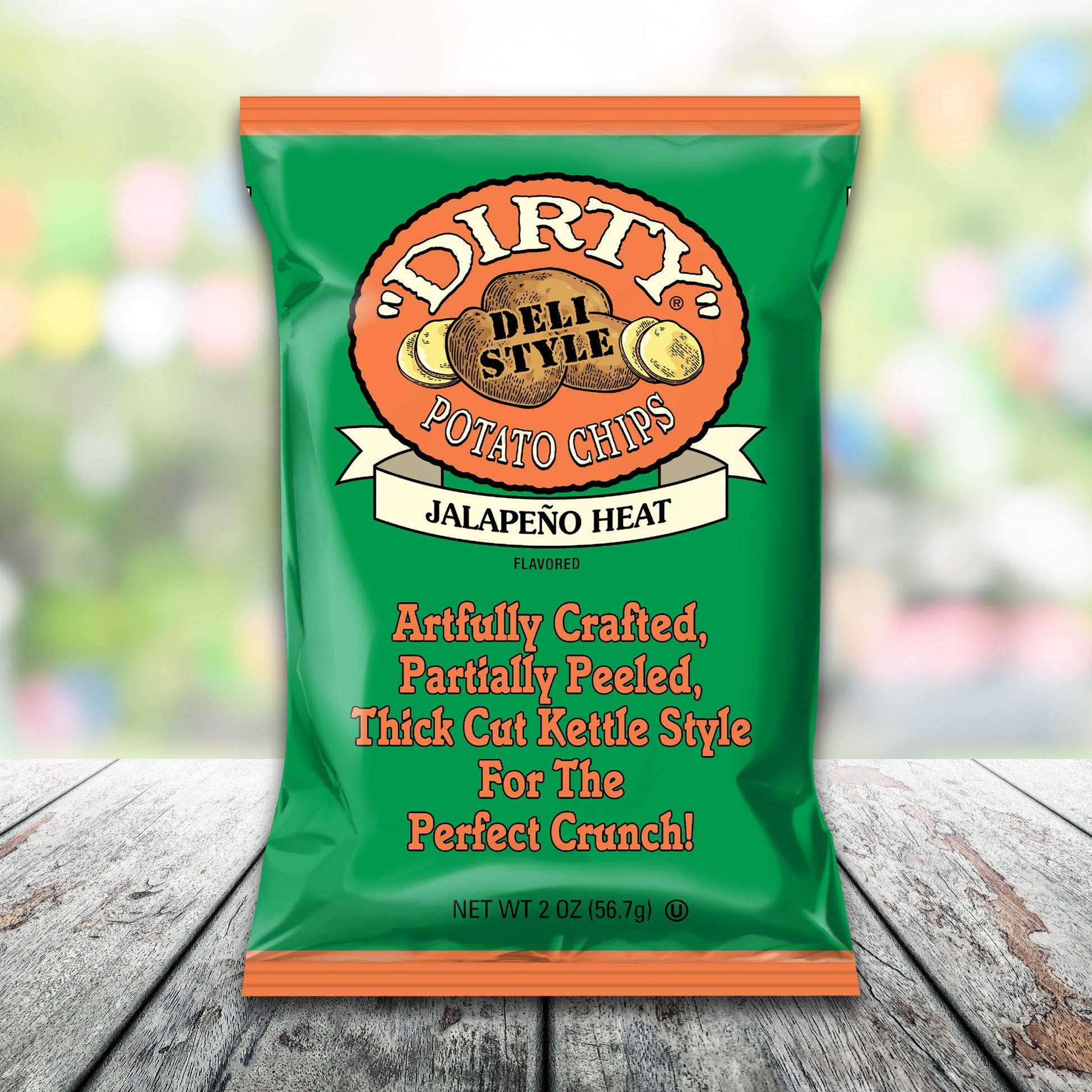 Green bag of Dirty Deli Style Jalapeño Heat potato chips on a wooden surface with a blurred colorful background.