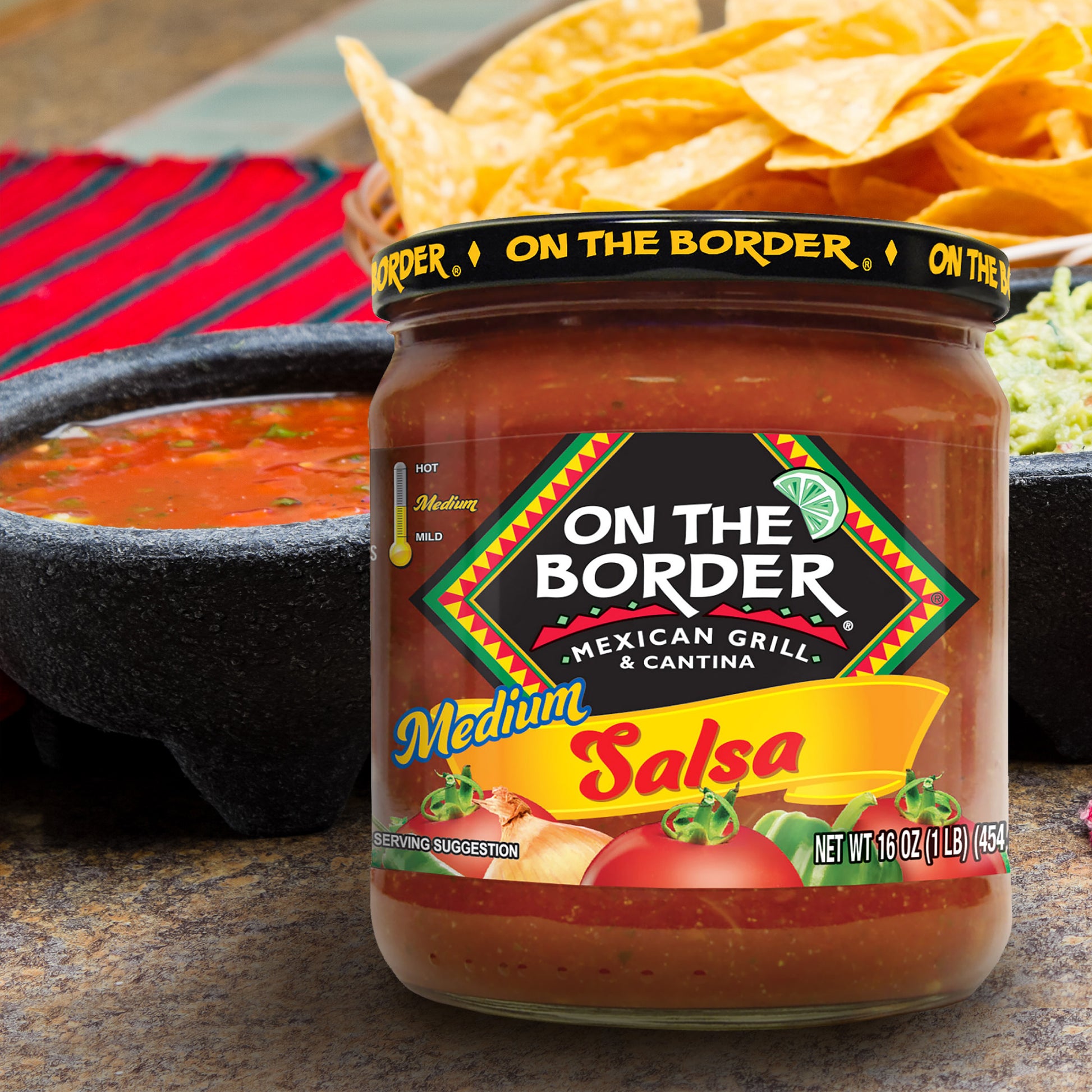 Jar of 'On The Border' salsa with tortilla chips and salsa in the background