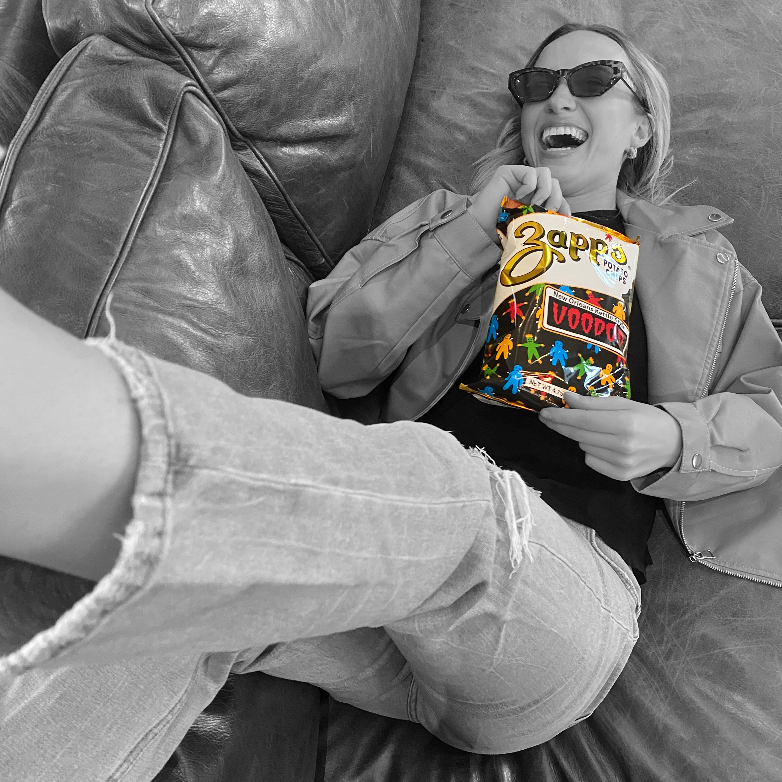 Person holding a colorful Zappos box on a gray couch