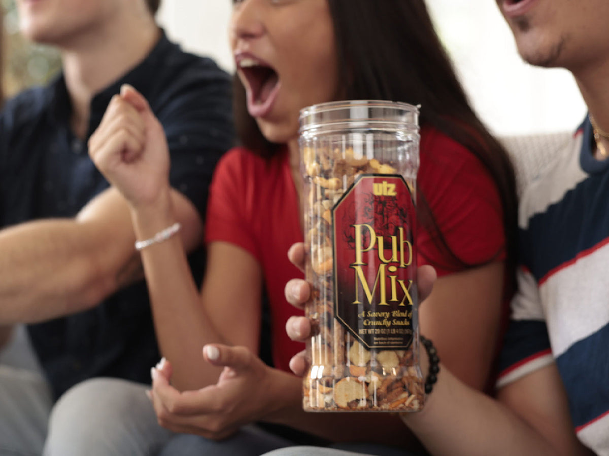 Person holding a container of pub mix with people in the background