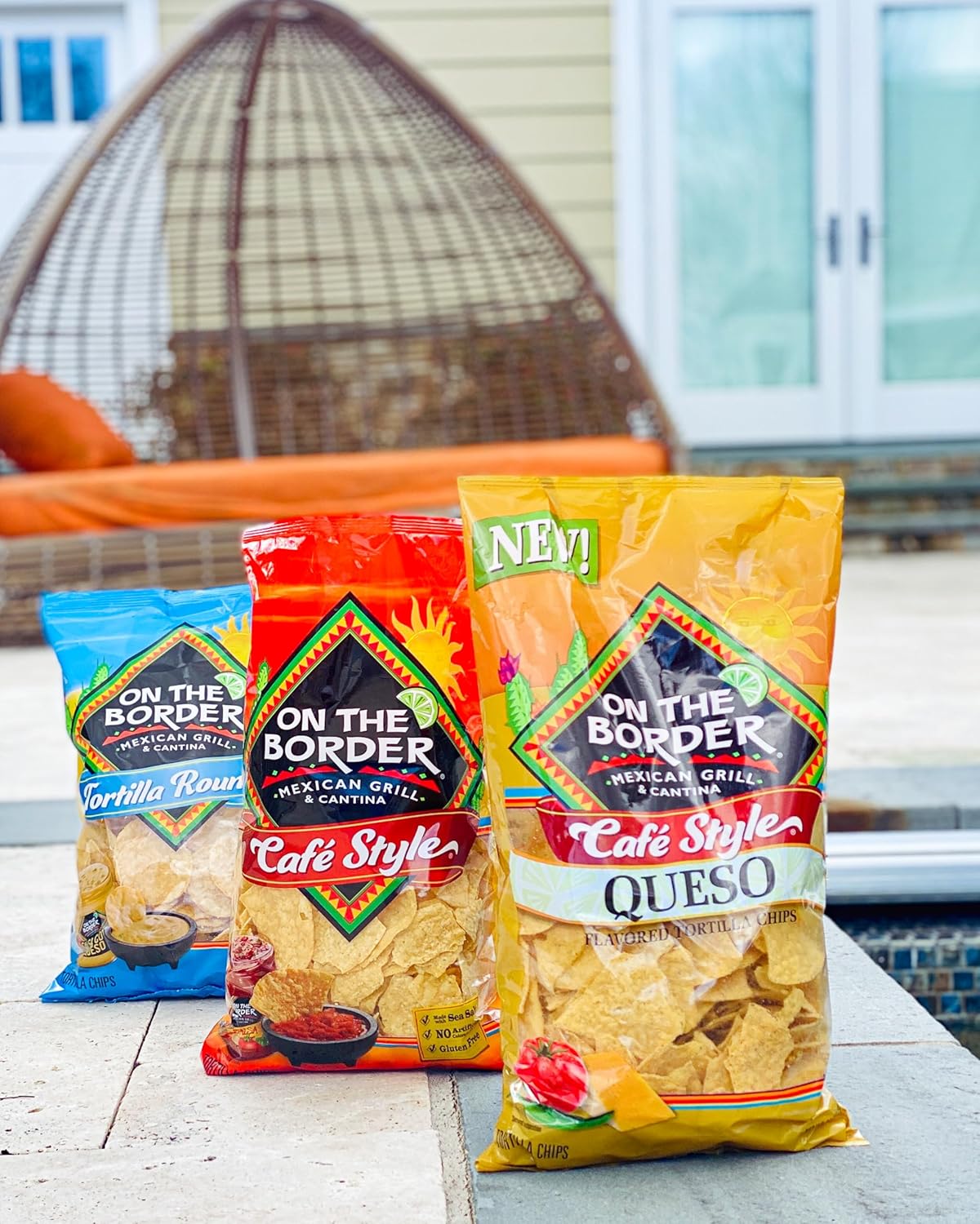 Three packages of 'On the Border' tortilla chips on a table with a blurred outdoor background.