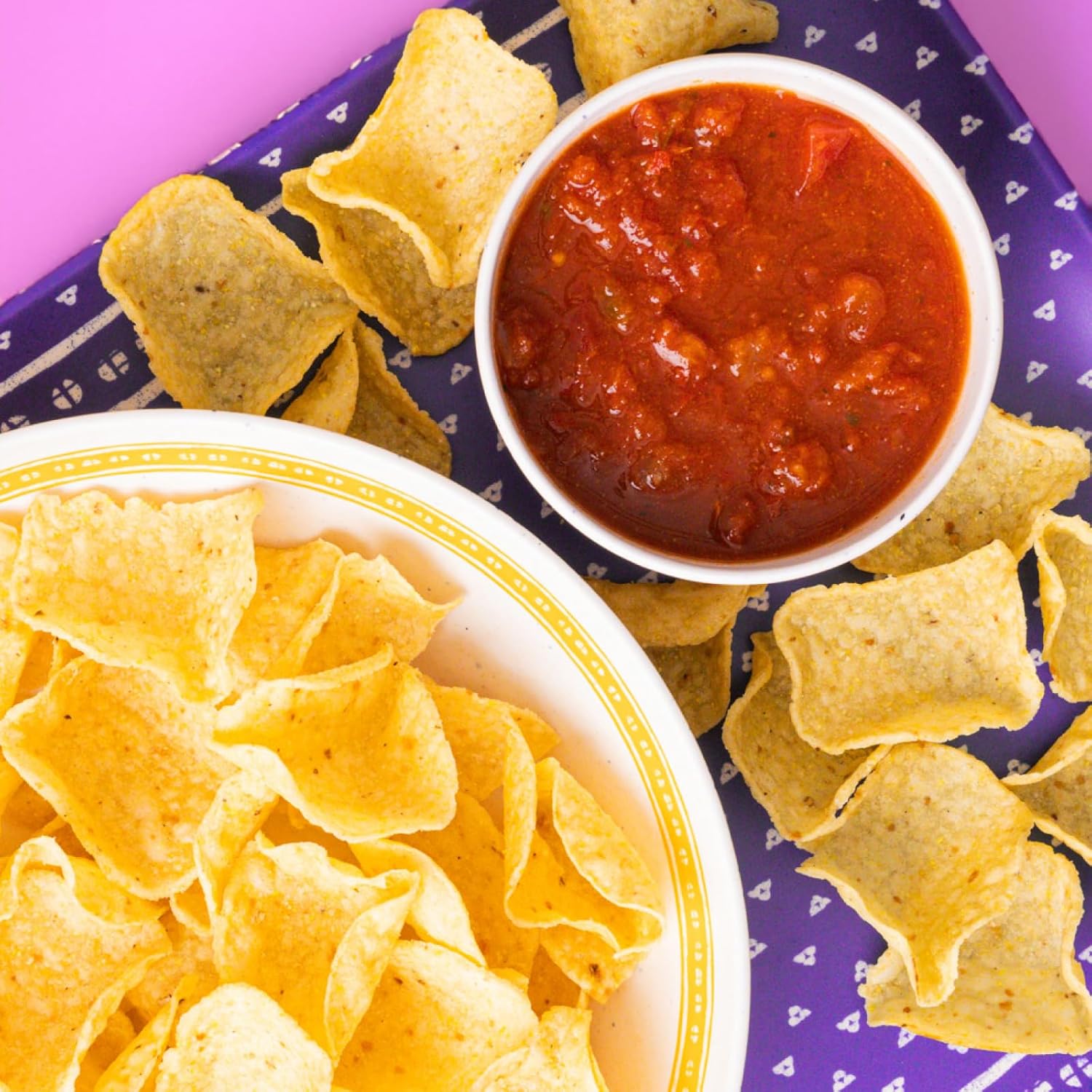Tortilla chips and salsa on a purple plate with white triangle pattern