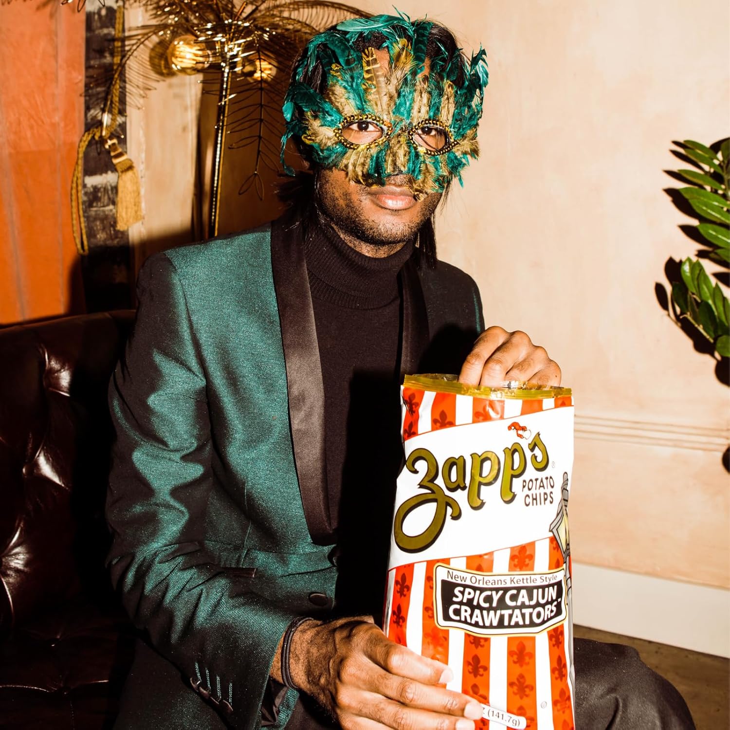 Person wearing a decorative mask holding a Zapp's Spicy Cajun Crawtator potato chip bag.