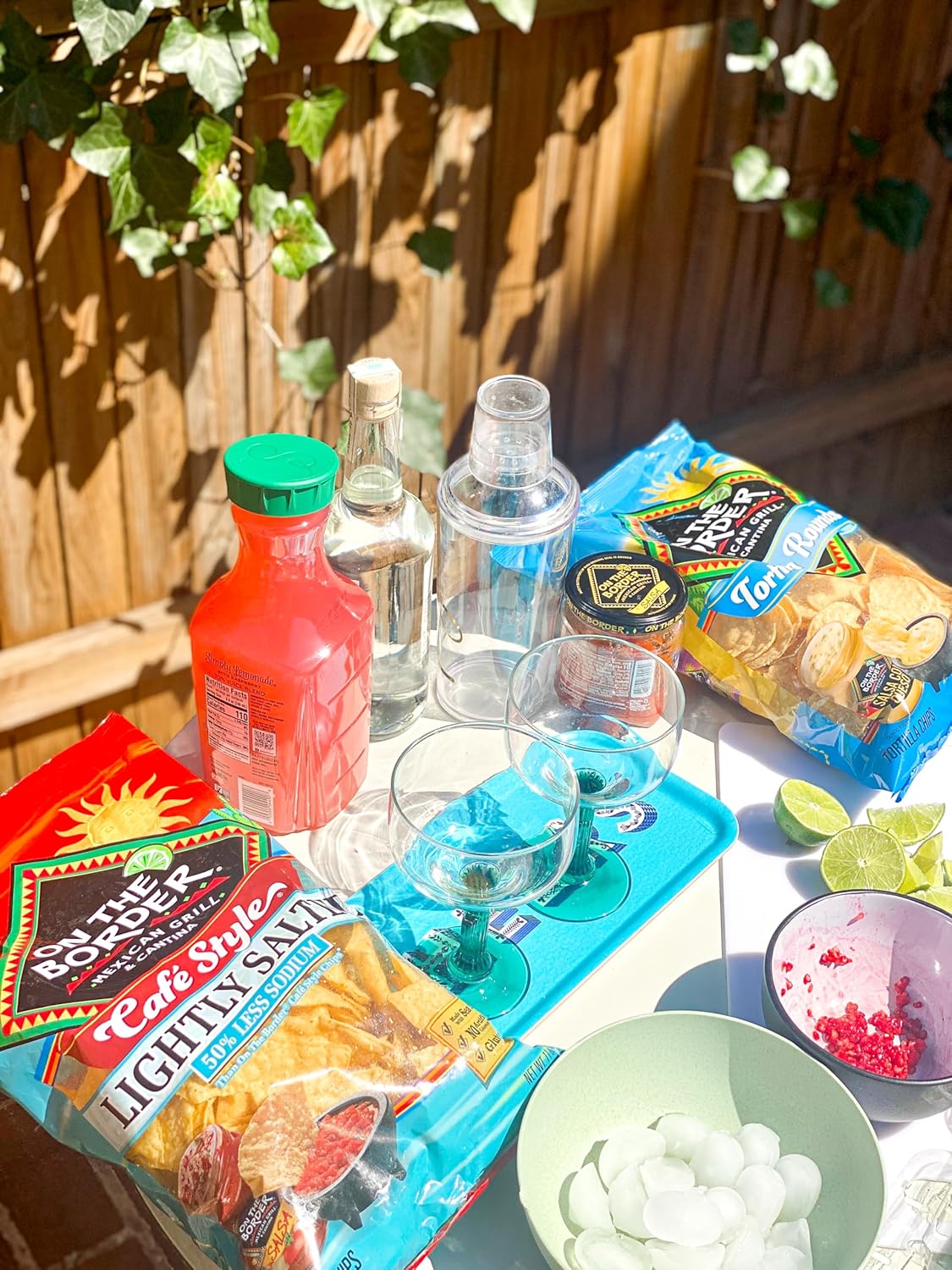 Outdoor setting with snacks, drinks, and a bottle of Kool-Aid on a table.
