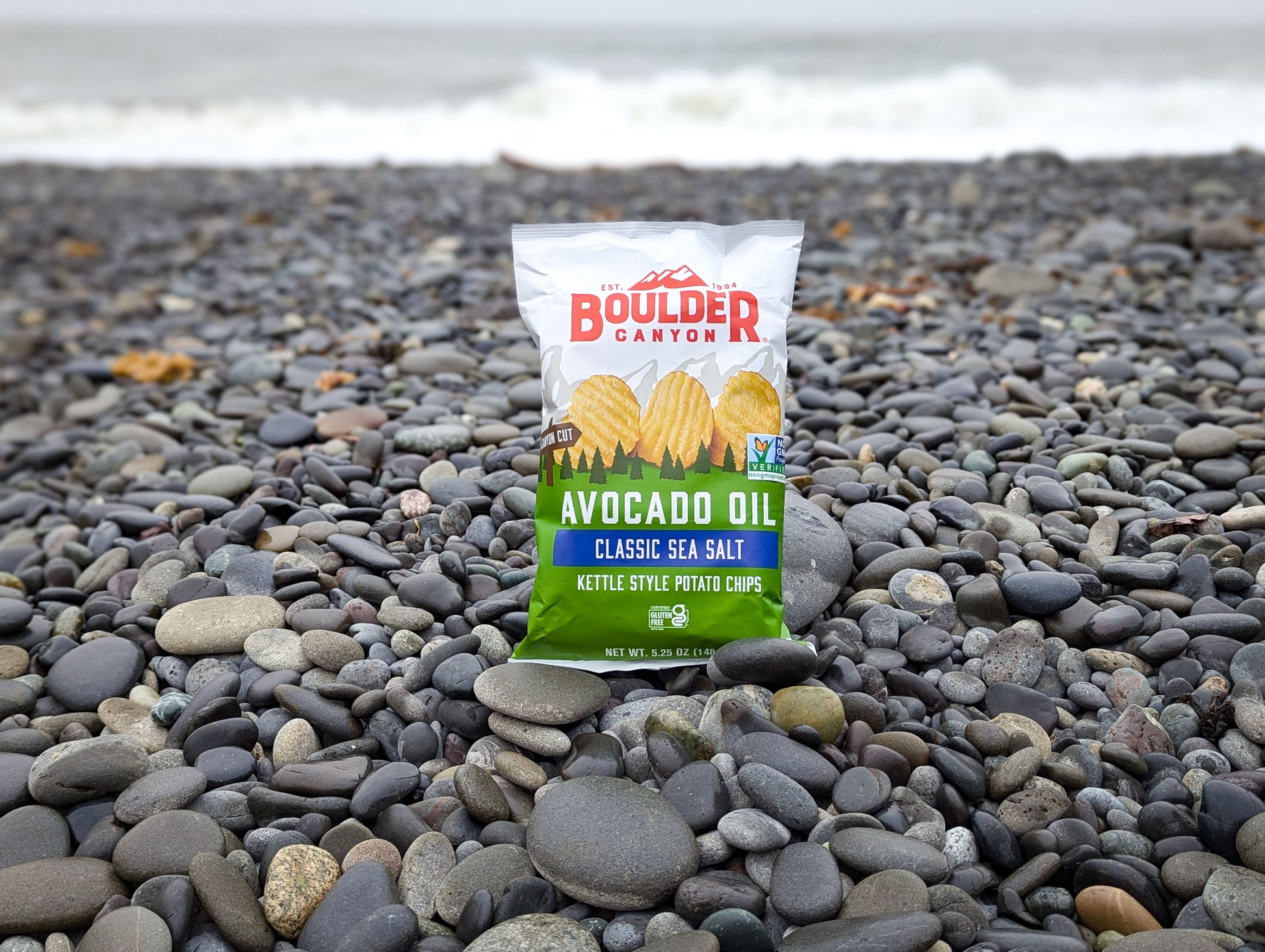 Boulder Carton avocado oil kettle-style potato chips package on a pebble beach