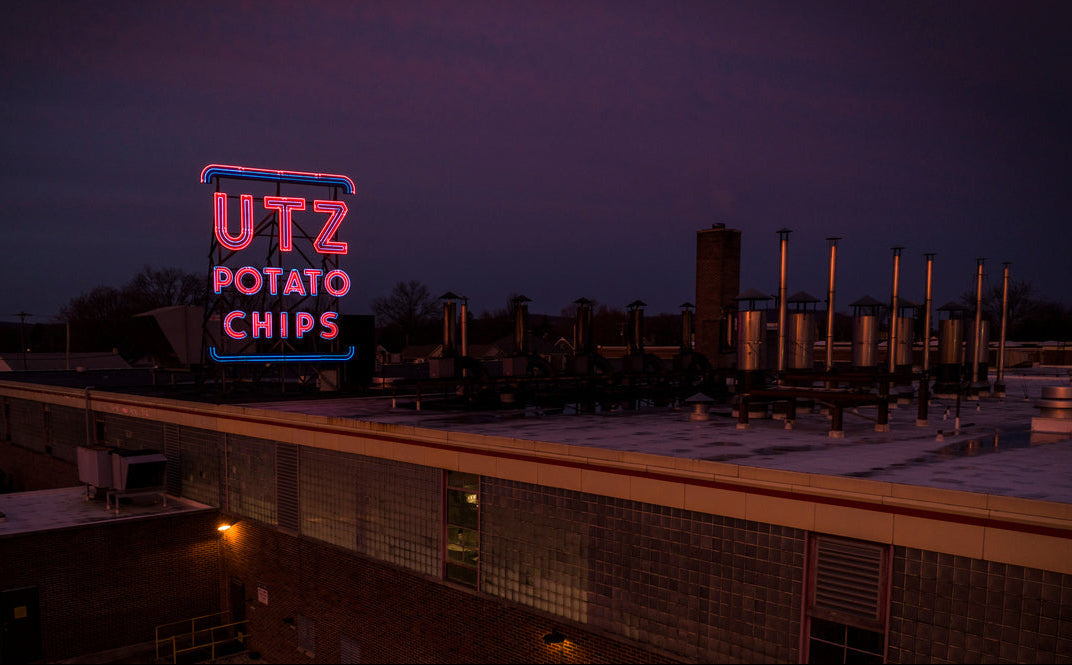 Neon sign for UTZ Potato Chips on a rooftop at night