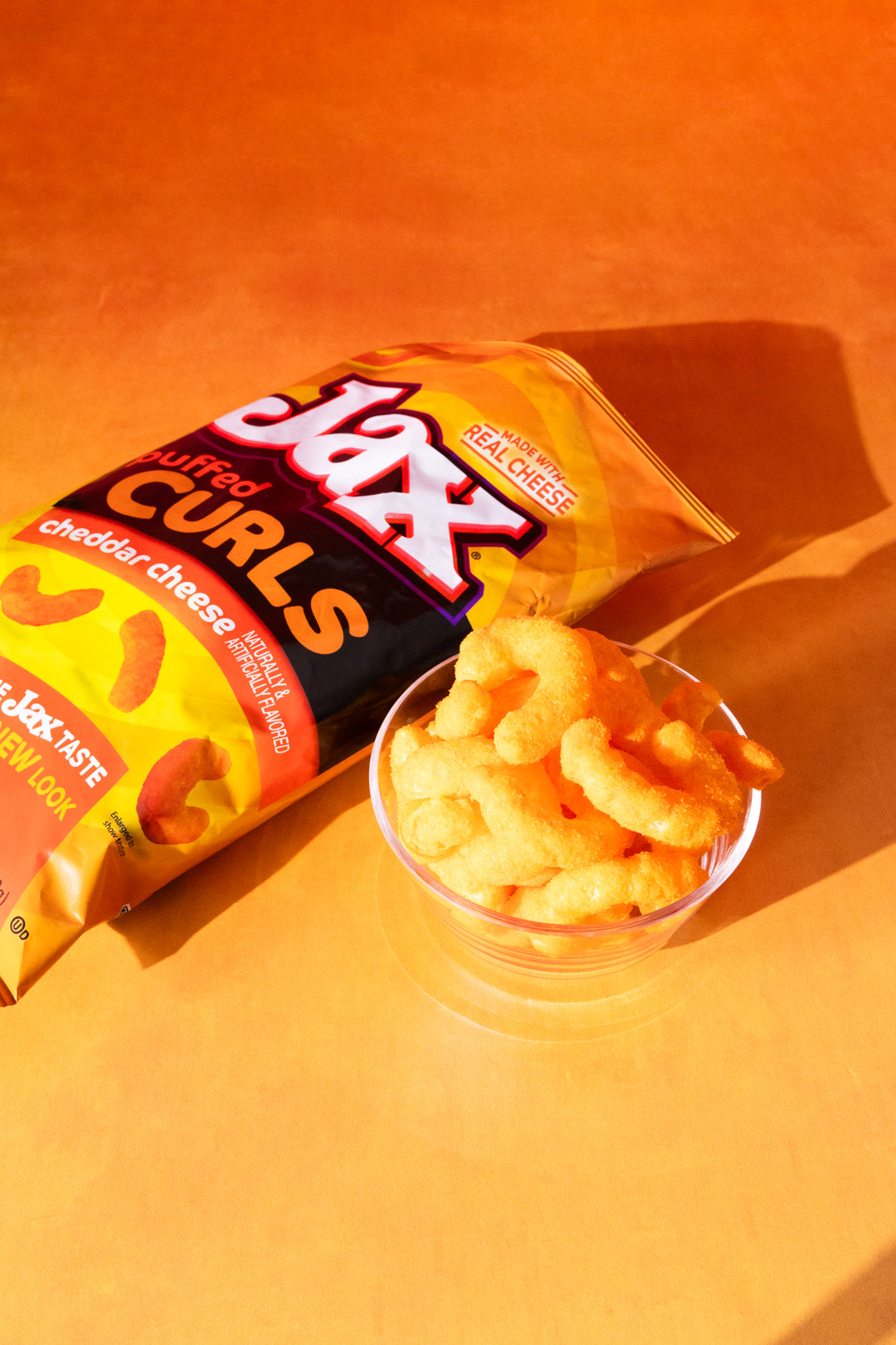 Bag of Jax Buttery Curls cheddar cheese flavored snacks on an orange background