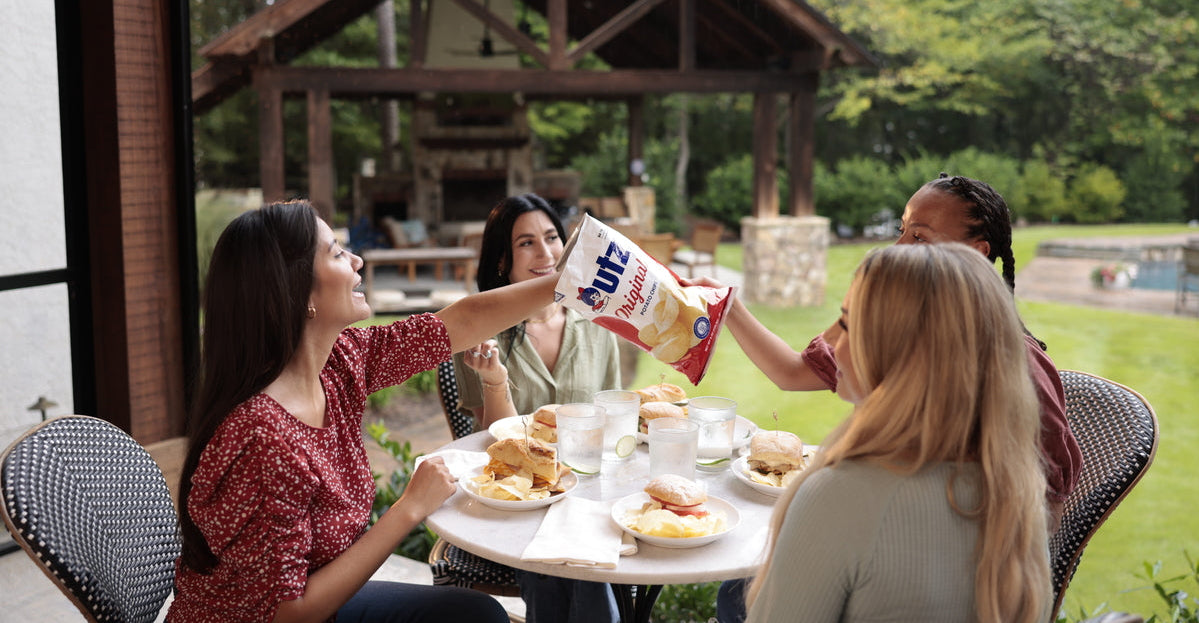 People enjoying a meal outdoors with a box of Kix cereal.