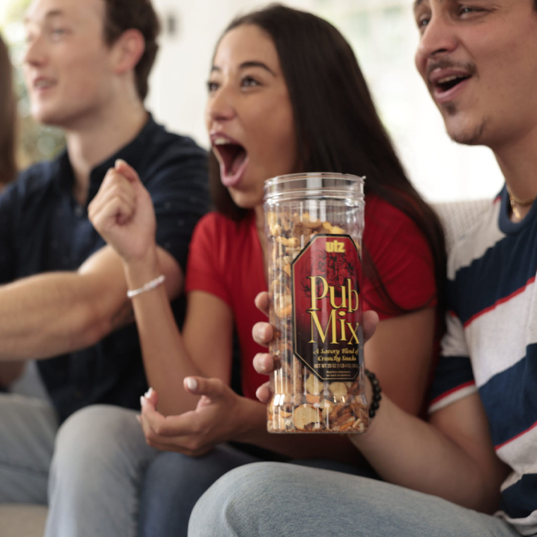 People sitting together holding a container of pub mix, with a focus on the product.