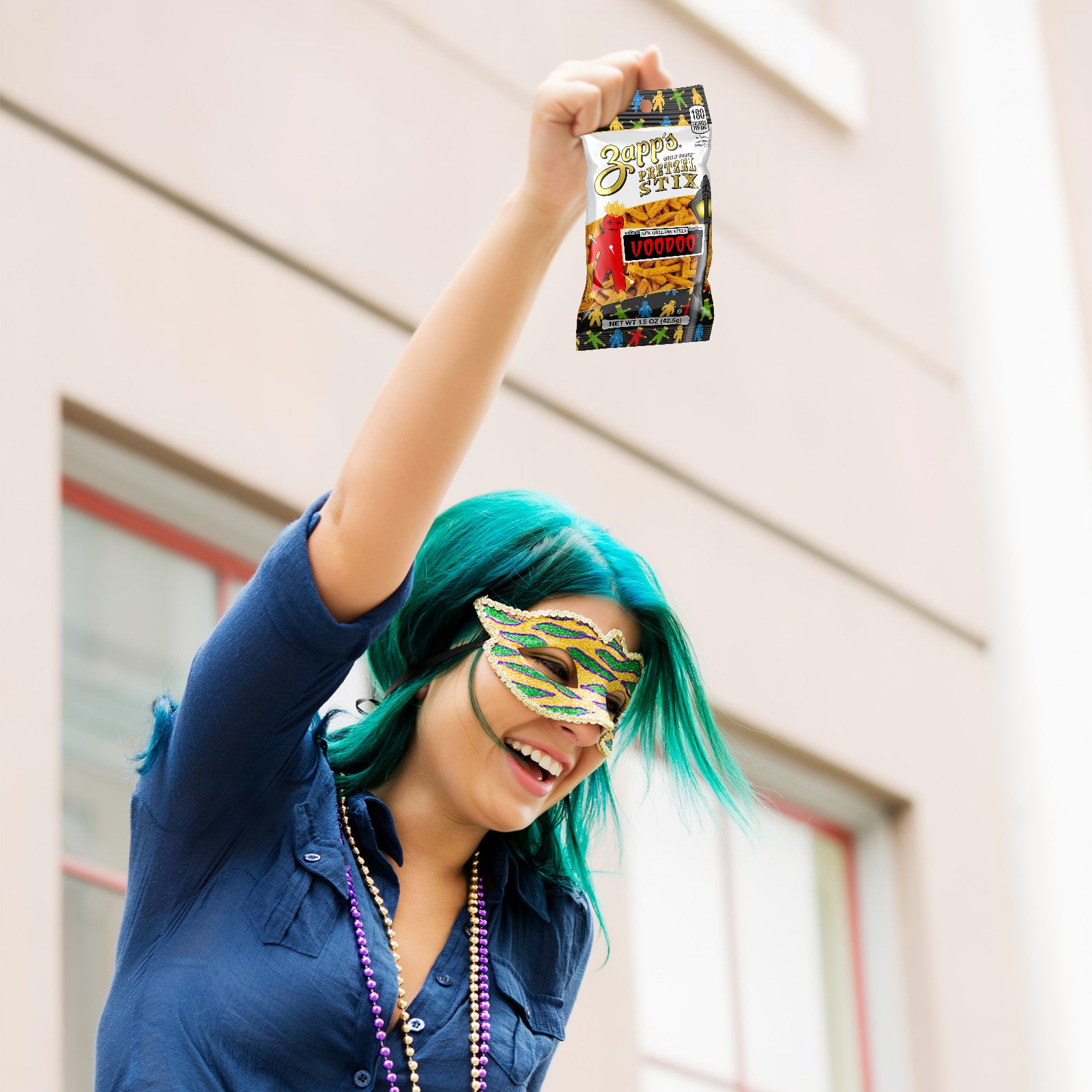 Person with teal hair and a mask holding a bag of candy