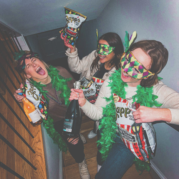 Three people celebrating with snacks and a bottle of champagne in a festive setting.
