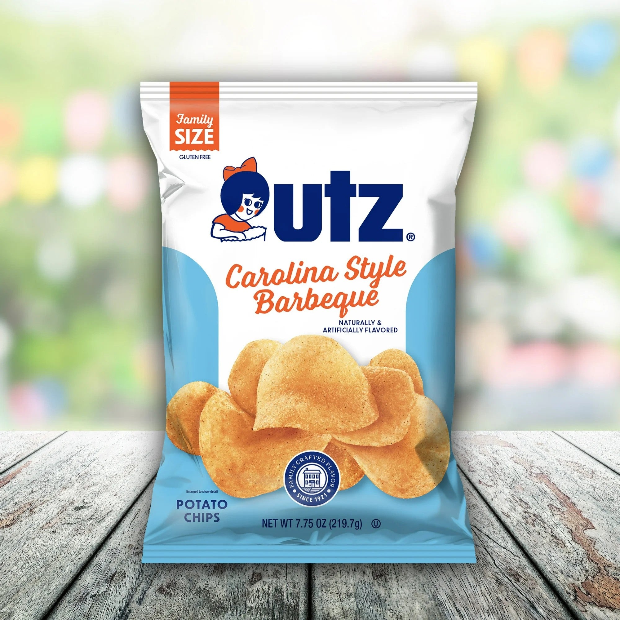 Utz Carolina Style Barbeque potato chips bag on a wooden surface with a blurred colorful background