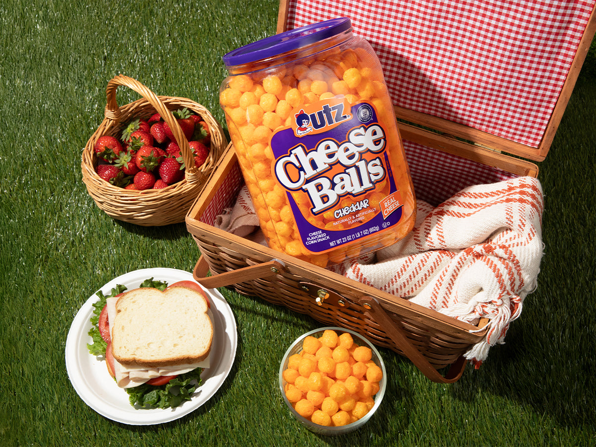Picnic setup with Quiznos Cheese Balls, strawberries, and a sandwich on grass.