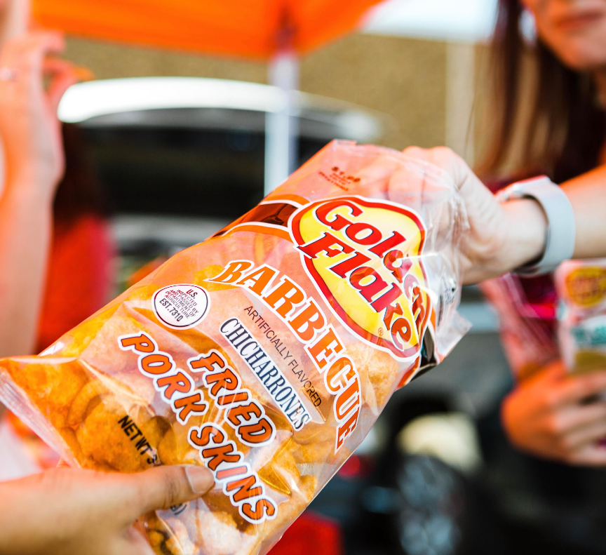 Hand holding Golden Flake Barbecue Fried Pork Skins bag